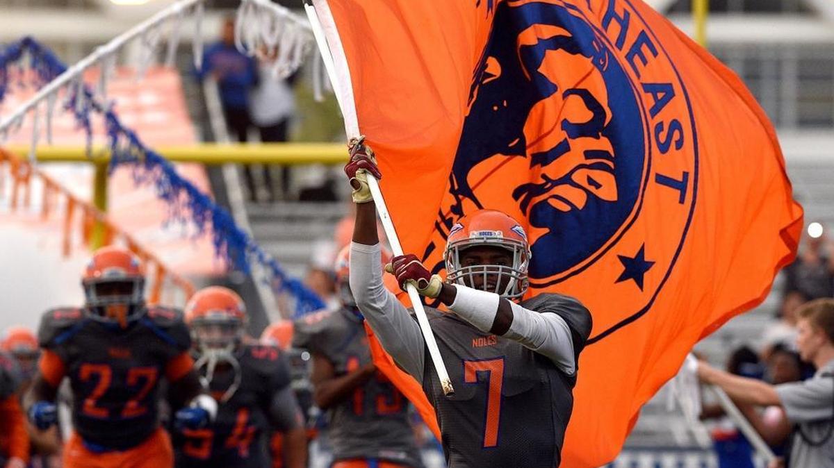 Southeast’s Dequan Williams runs onto the field with the team flag before a game at John Kiker Memorial Field.