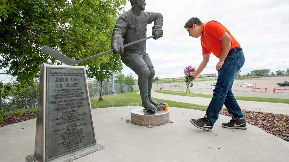 Matt Adamowski lays flowers at a statue of Gordie Howe at the Sasktel Centre in Saskatoon, Saskatchewan, on Friday.
