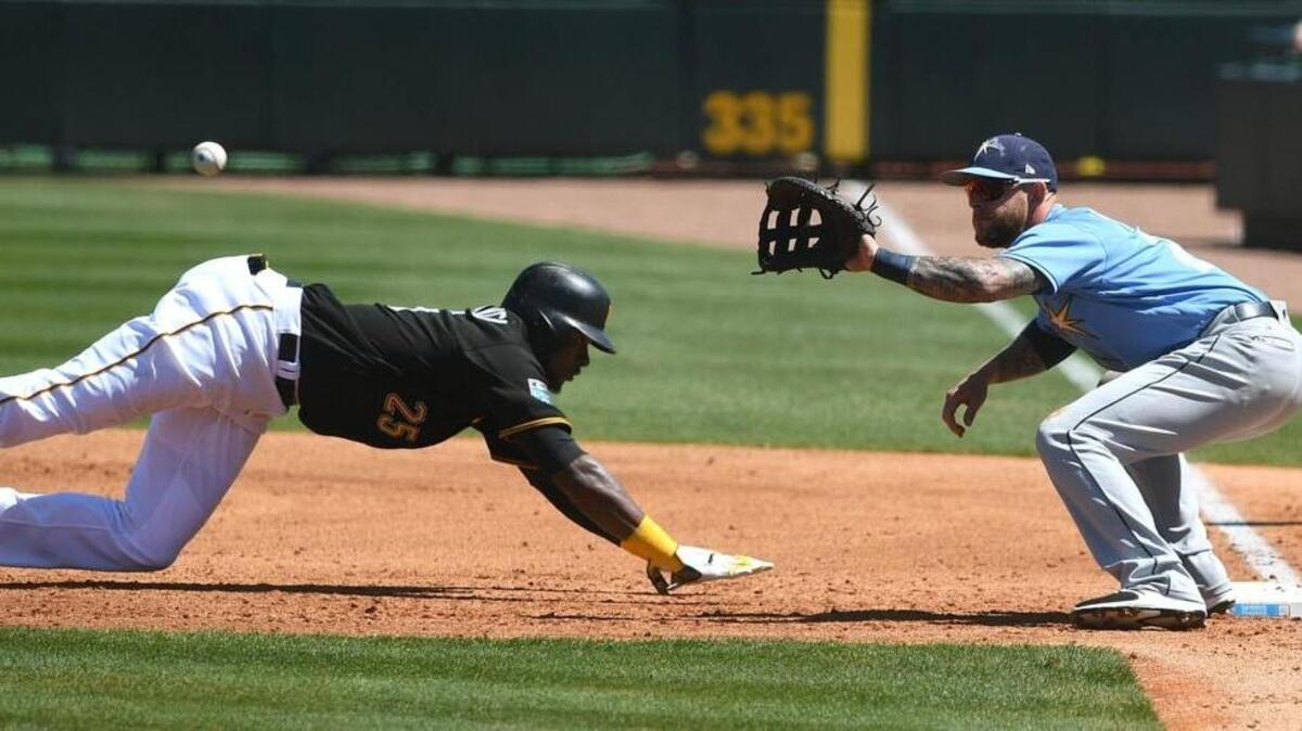 The Pirates’ Gregory Polanco dives back to first base as Rays first baseman Brandon Snyder awaits the throw during Wednesday’s Grapefruit League game between Pittsburgh and Tampa Bay at LECOM Park in Bradenton.