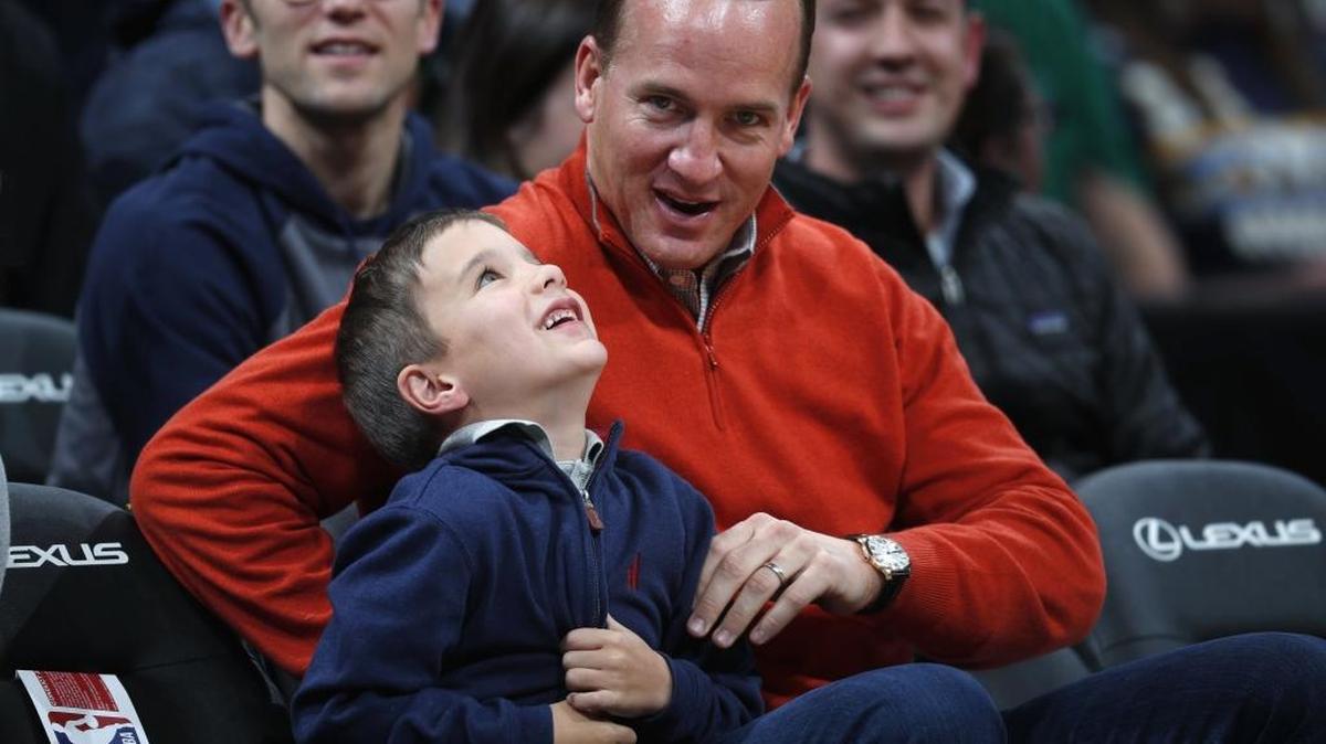 Former Denver Broncos quarterback Peyton Manning and his 6-year-old son, Marshall, watch the Memphis Grizzlies play the Denver Nuggets during the second half of an NBA basketball game Friday, Jan. 12, 2018, in Denver. The Nuggets won 87-78.