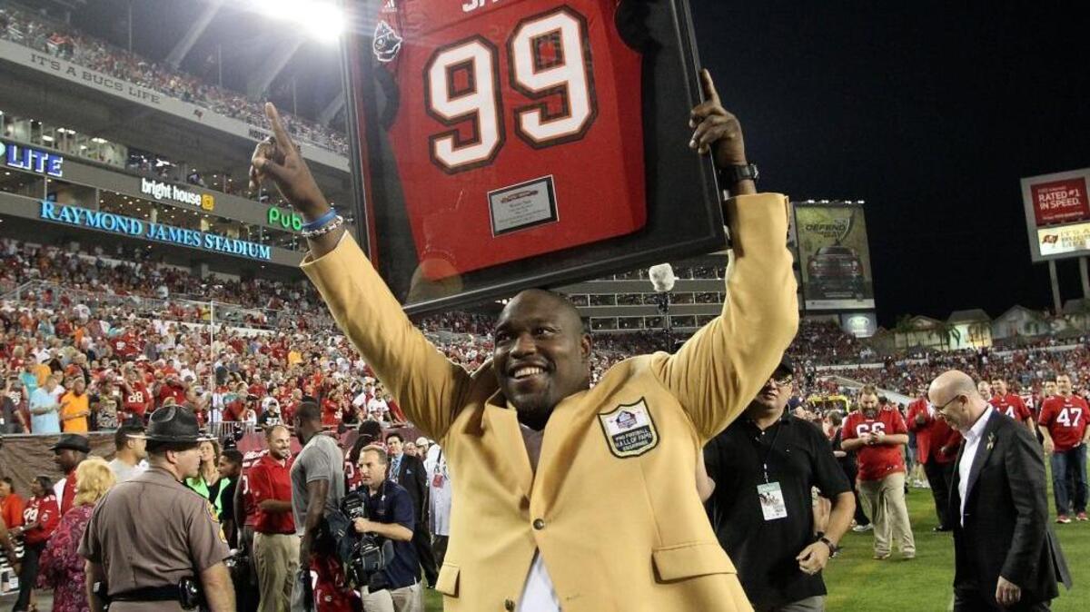 Warren Sapp carries his framed jersey off the field after he is inducted into the Tampa Bay Buccaneers’ Ring of Honor during halftime of Tampa Bay’s game against Miami at Raymond James Stadium in Tampa on Nov. 11, 2013. Sapp has announced he’s starting to suffer the effects of the many hits he took during his football career and he’s donating his brain for concussion research.