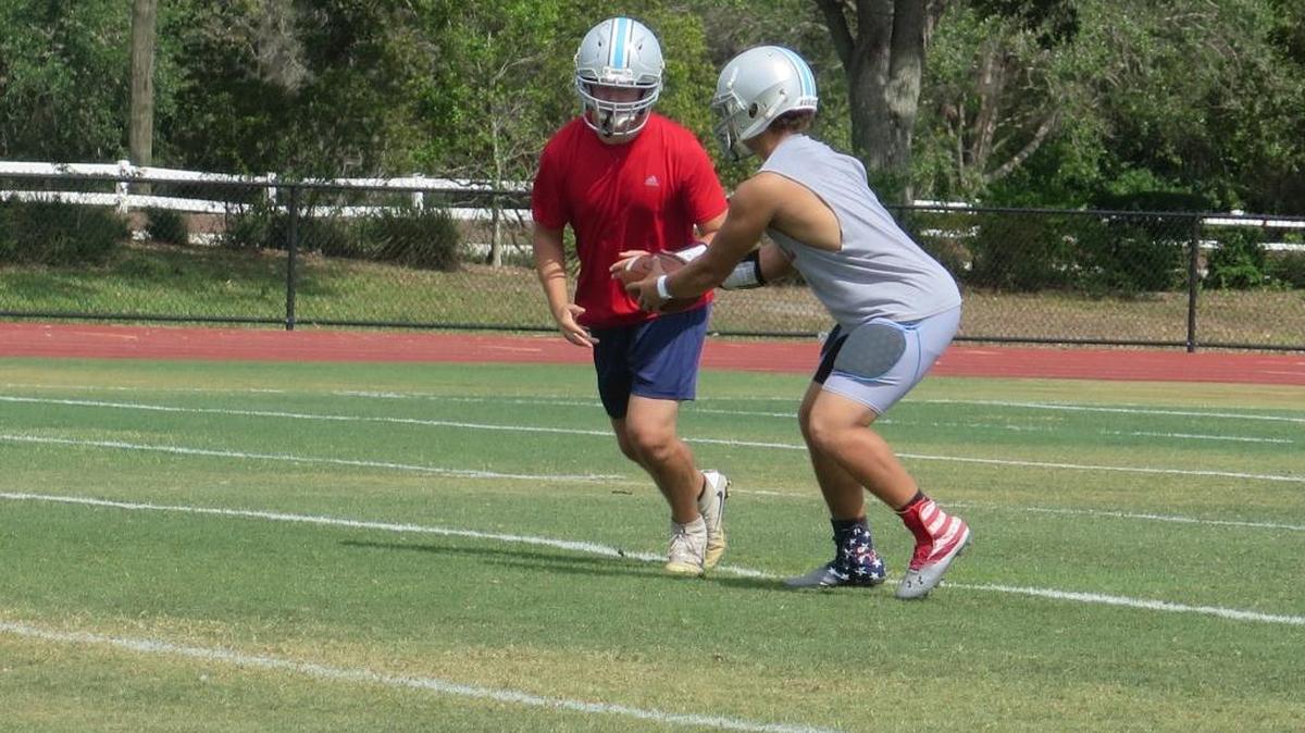 Dakota Dickerson (right) fakes a handoff during practice at Thunder Stadium. The rising senior will start at quarterback in Out-of-Door Academy’s new triple-option offense.