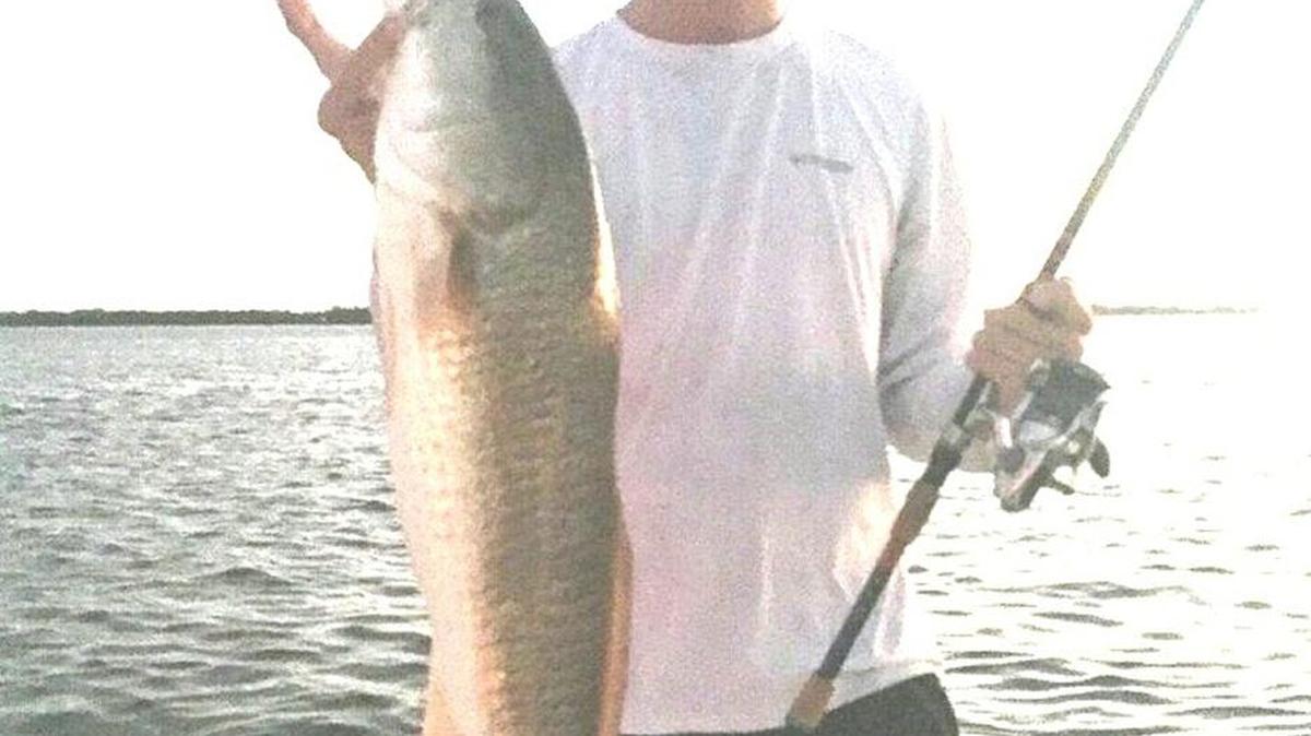 Kyle Grimes holds a redfish he caught Wednesday night on the edge of a sandbar at low tide.