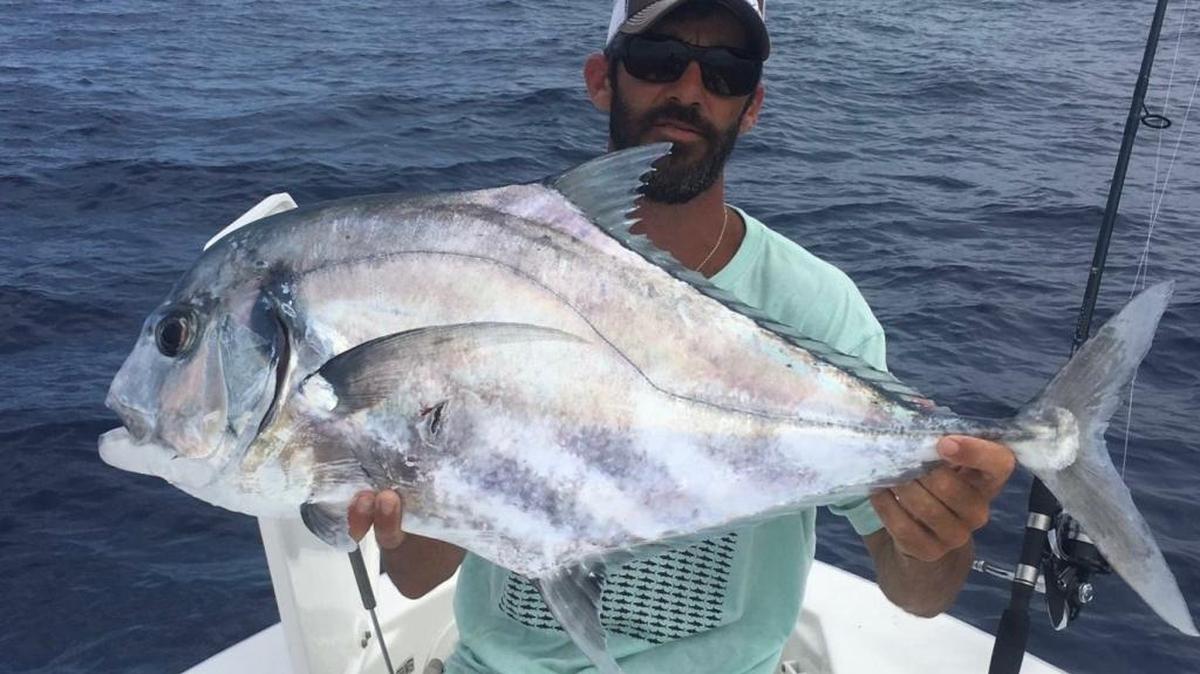 David Lee White hoists his 30-pound African pompano that he caught last week over a spring.