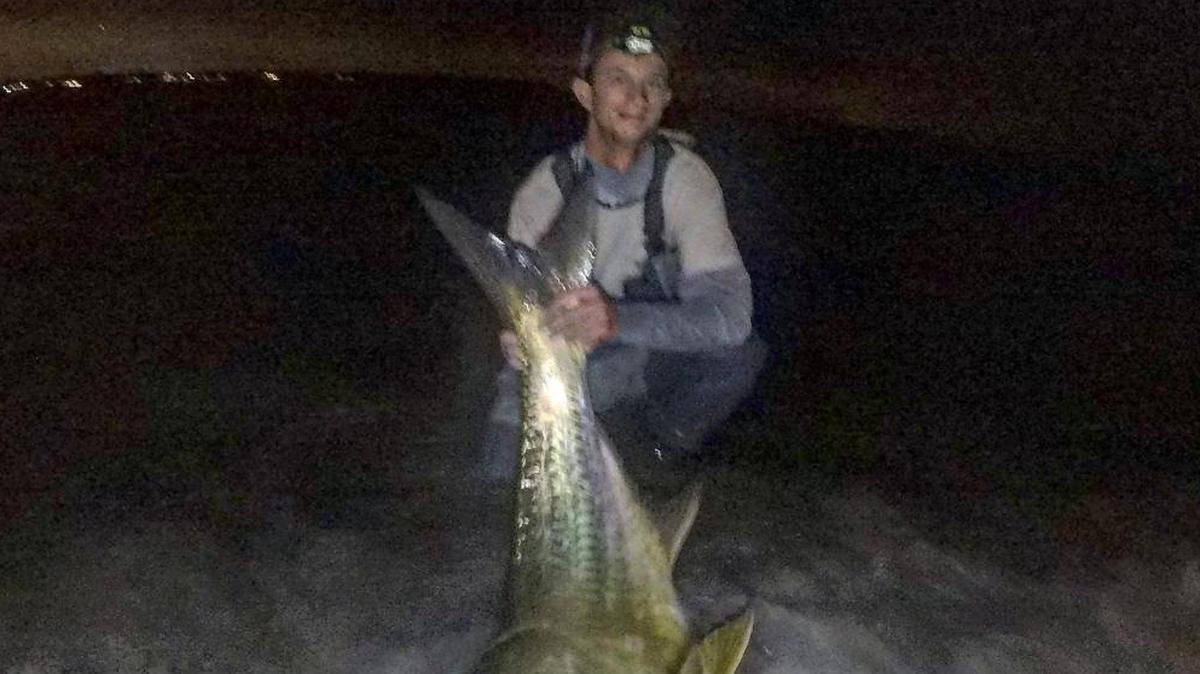 Eric Whitted with a 100-pound tarpon caught wading along a channel edge at night.
