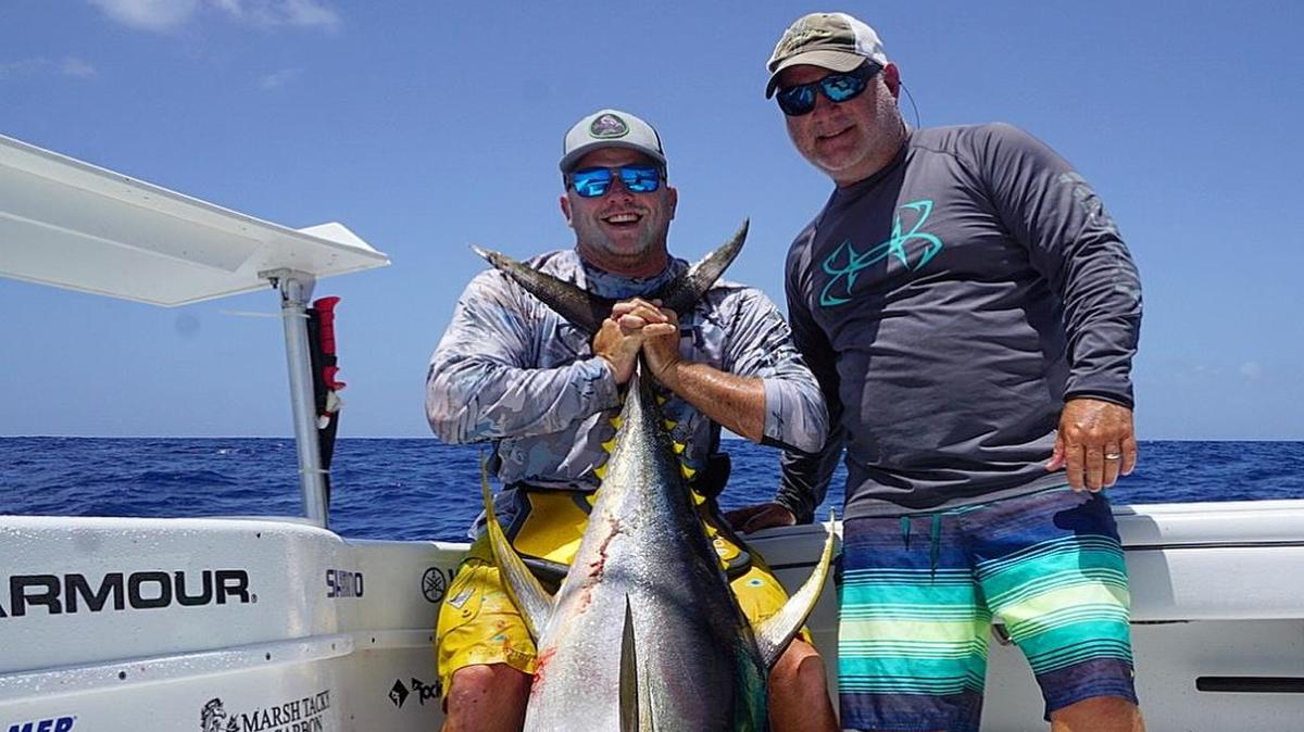 Craig Jackson holds a 94.52-pound yellowfin tuna caught during the Sarasota Slam beside Brian Turner.