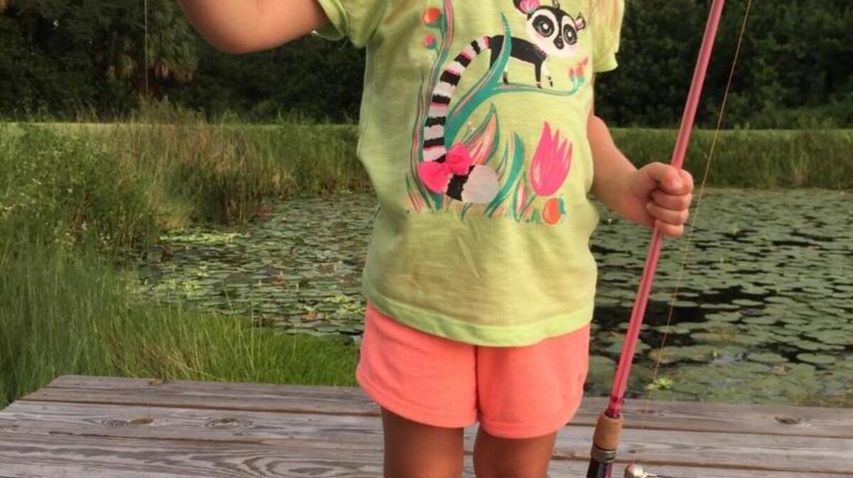 Four-year-old Juliet Chapman poses with her first fish, a bluegill she promptly named Fishy the Greg, before releasing it back into an area pond this week.