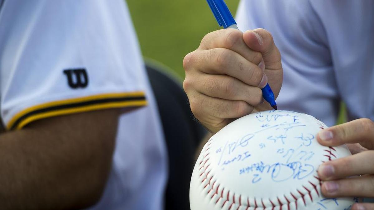 Marauders players sign oversize baseballs for fans during the Meet the Marauders event before the season.
