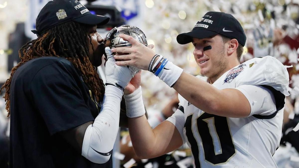 UCF linebacker Shaquem Griffin, left, kisses the championship trophy as quarterback McKenzie Milton looks on after the Peach Bowl, which the Knights won 34-27 to finish the season as the only undefeated team in FBS.